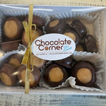 A boxed assortment of chocolate-covered ice cream candies with a tan center, presented in a white box with paper cups and tied with a gold ribbon. A round label reads 'Chocolate Corner Ice Cream'.