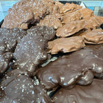 Close-up of assorted chocolate-covered snacks or cookies in two tones, including milk-chocolate brown and tan, with some sprinkled coarse salt.
